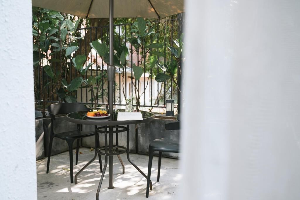 Un patio al aire libre con una mesa redonda, dos sillas y un arreglo de plantas pequeño.