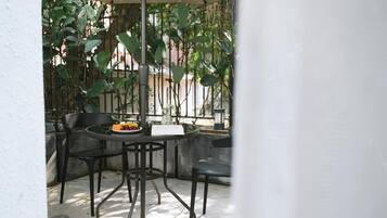 Un patio al aire libre con una mesa redonda, dos sillas y un arreglo de plantas pequeño.