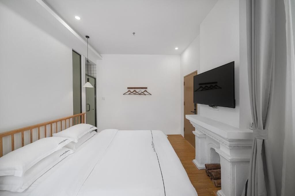 Un dormitorio moderno con una cama grande, un televisor en la pared y una chimenea.