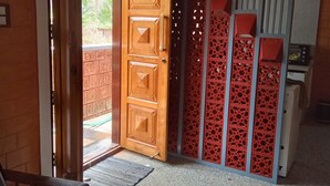 A room with a wooden door, a patterned rug, a red decorative partition, and a microwave. - DhruvDhanush(2-bedroom with AC/2 attached bathroom in lovely Ullal/deralakatte (Ullal)