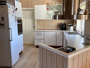 Eine kleine Küche mit Kühlschrank, Backofen und Kaffeemaschine.