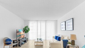 A living room with a sofa, TV, coffee table, and a plant. - Oceanview Comfort Elegant S Ocean Drive (Hollywood)