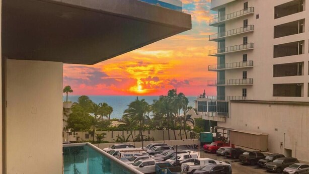 A hotel with a pool, a parking lot, and a view of the sunset over the ocean. - Oceanview Comfort Elegant S Ocean Drive (Hollywood)
