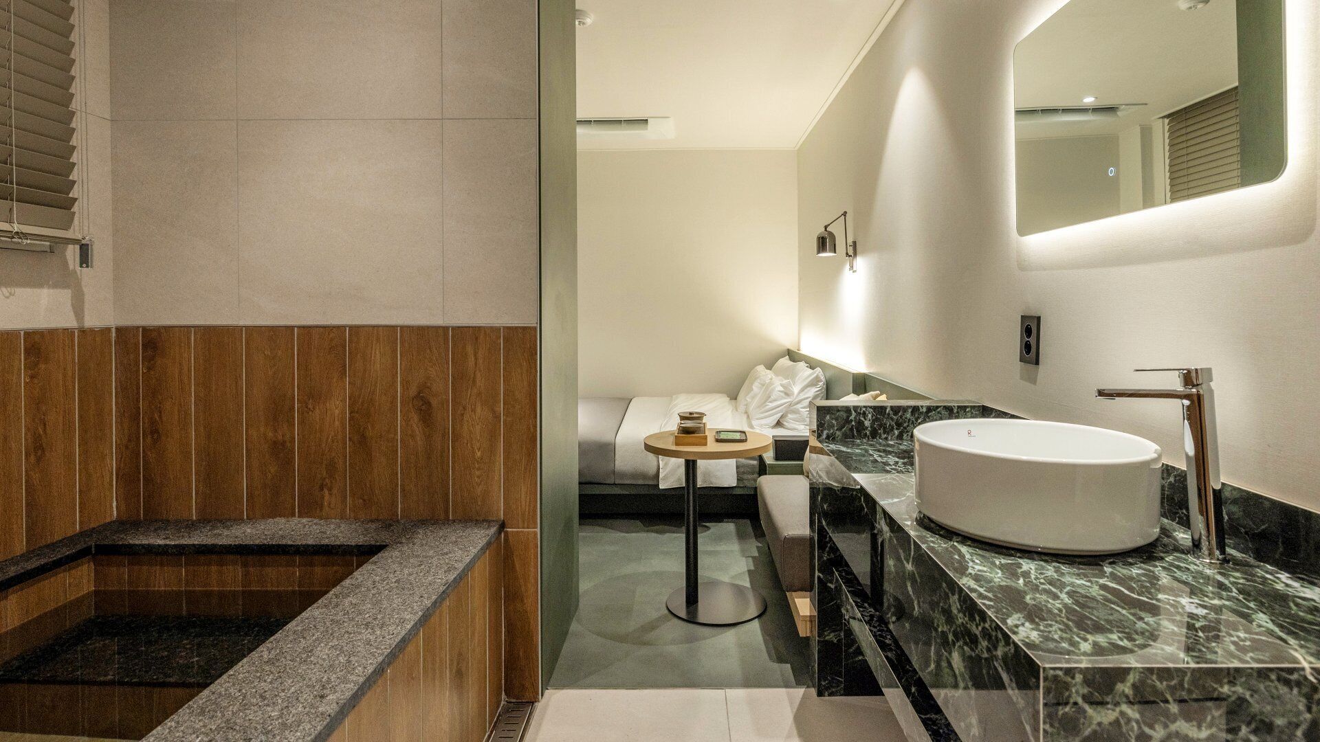 Un baño moderno con una bañera independiente, un lavabo redondo y una pequeña mesa redonda.