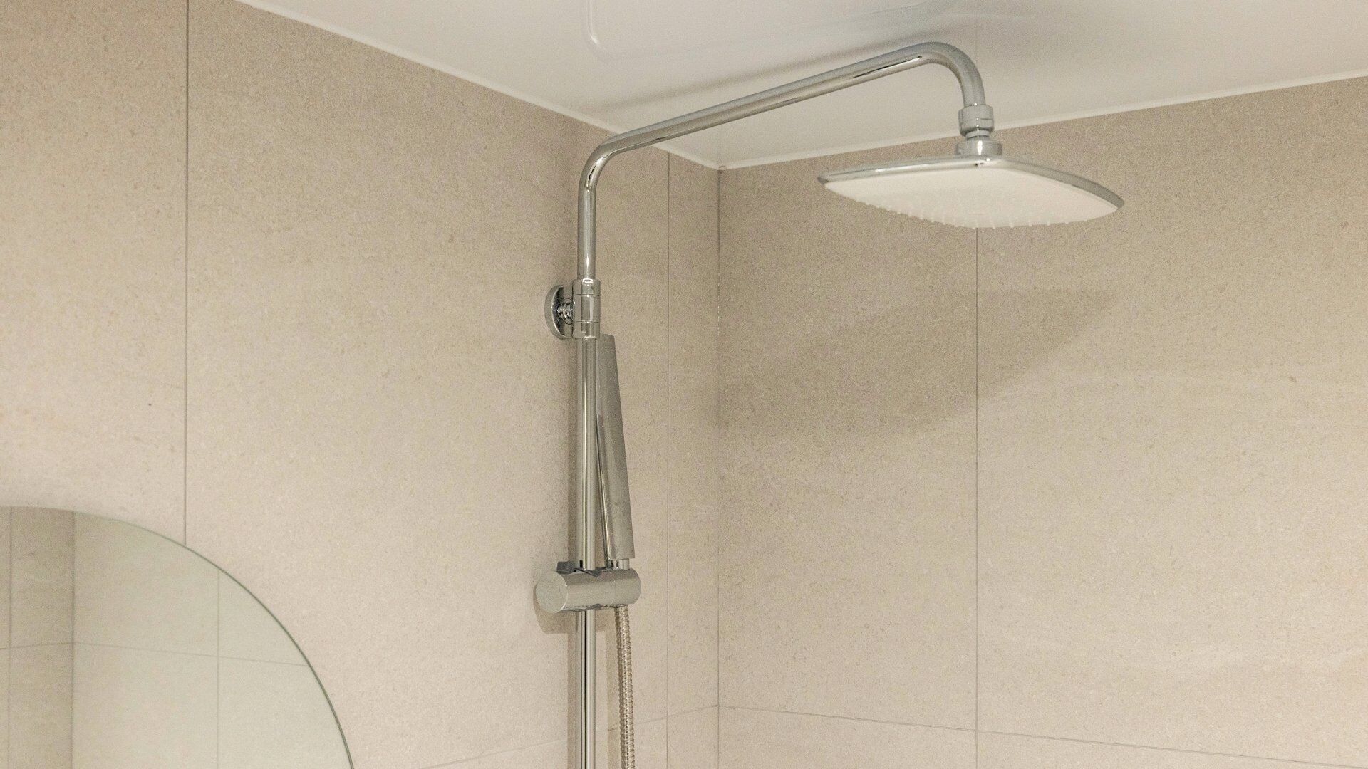 A shower with a curved head and a handheld showerhead.