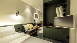 Una habitación de hotel moderna con cama, escritorio, silla, televisor y armario.