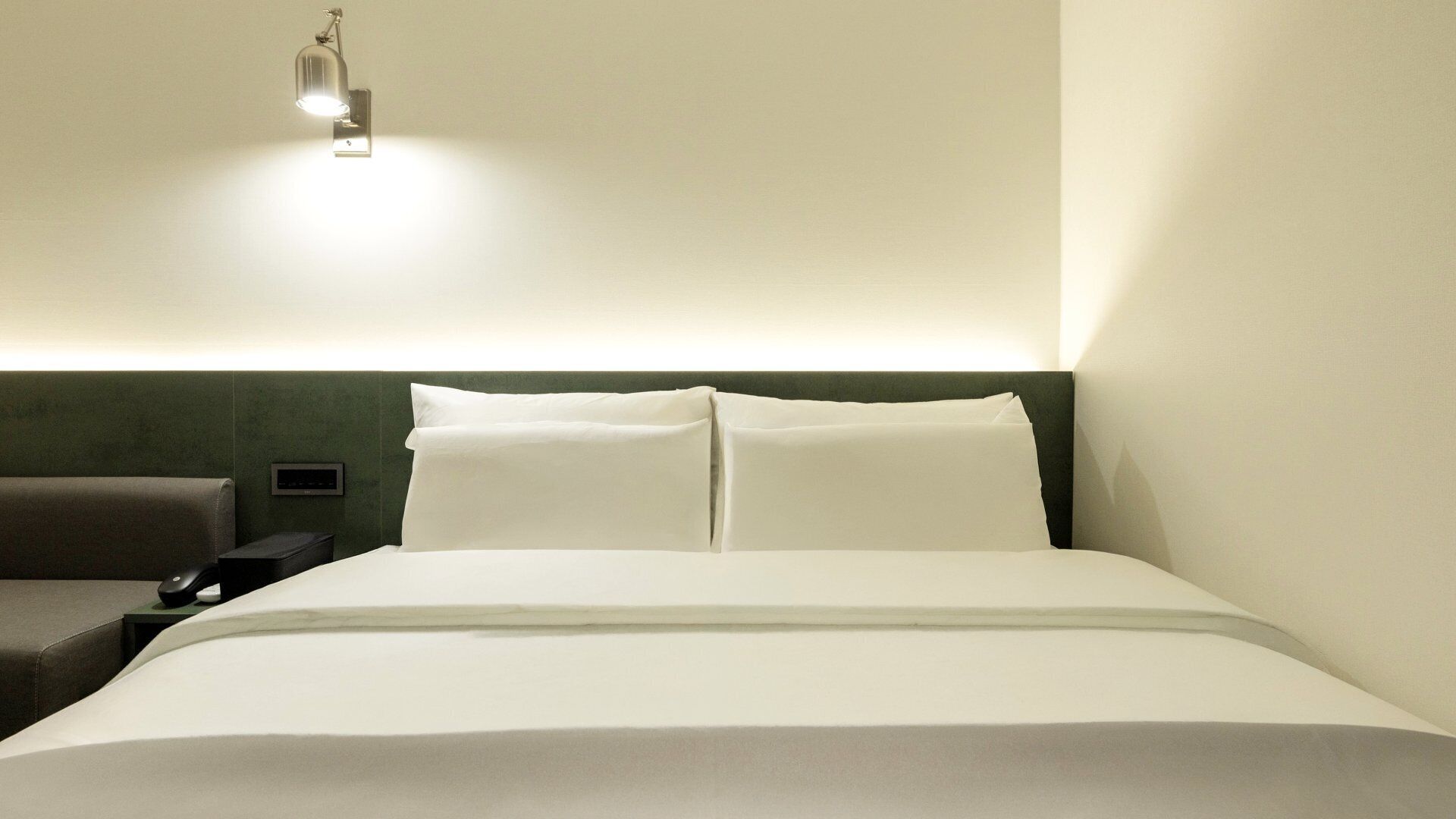 Una habitación de hotel con cama, mesita de noche, lámpara y una silla.