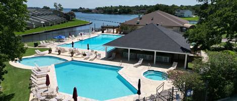 A swimming pool area with multiple pools, lounge chairs, and a covered seating area.