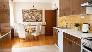 Eine moderne Küche mit Holzausstattung, einem Geschirrspüler, einem Herd und einem Essbereich mit Tisch und Stühlen.