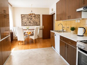 Een moderne keuken met houten kasten, een vaatwasser, een fornuis en een eethoek met een tafel en stoelen.