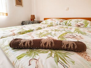 Una cama con estampado de jirafa y elefante, un cabecero de madera y una mesita de noche con una lámpara.