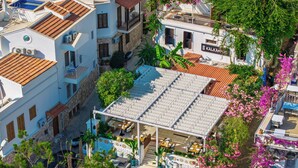 A rooftop terrace with outdoor seating, surrounded by buildings with stone facades and balconies.