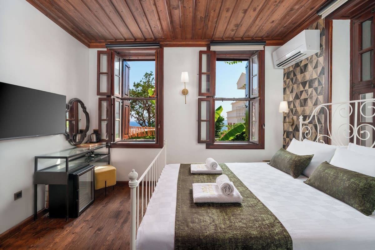 Quarto com cama, escrivaninha, televisão e janela com ar condicionado.