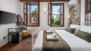 A bedroom with a bed, a desk, a TV, and a window with an air conditioner.