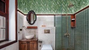 A bathroom with a wooden vanity, a white sink, a toilet, a shower with a glass door, and a mirror on the wall.