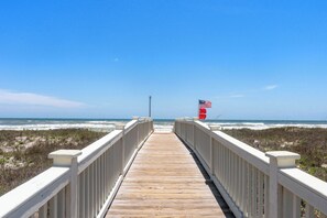 Ein Holzsteg führt zu einem Strand mit einer amerikanischen Flagge.
