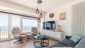 A modern living room with a balcony, a flat-screen TV, and a view of the sea. - Sea view and comfort in Middelkerke (Middelkerke)