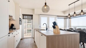 A modern kitchen with a central island, a built-in stove, and a view to the outside. - Sea view and comfort in Middelkerke (Middelkerke)
