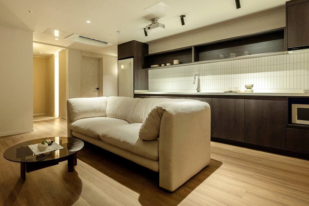 Una sala moderna con un sofá, una mesa de centro y una cocina con un lavaplatos y armarios.