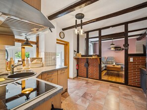 A modern kitchen with a large island, a built-in oven, and a dining area with a brick wall and a sofa. - Apartment in Straßberg in the Harz Mountains (Straßberg)