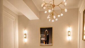 A bedroom with a large bed, bedside tables, a chandelier, and wall sconces.