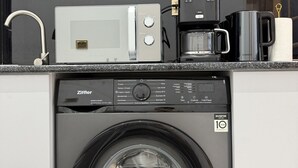 A compact kitchen with a washing machine, a microwave, and a coffee maker.