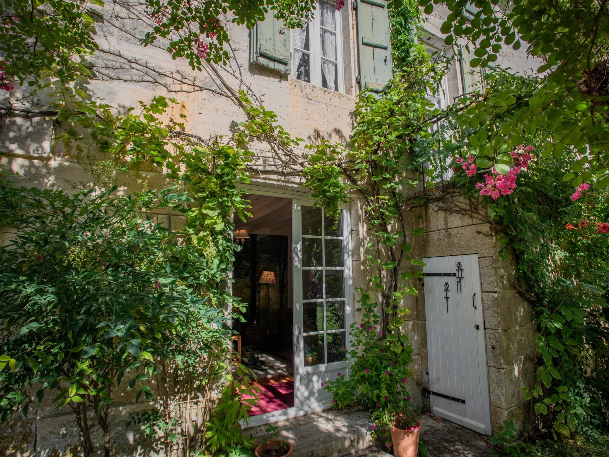 A courtyard with a white door, a small garden area, and a stone wall.