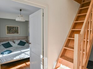A bedroom with a bed, pillows, a hanging light fixture, and a wooden staircase. - Charming home with garden and private pool. (Edon)