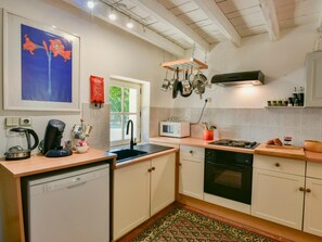 A kitchen with a dishwasher, stove, microwave, and hanging pots. - Charming home with garden and private pool. (Edon)