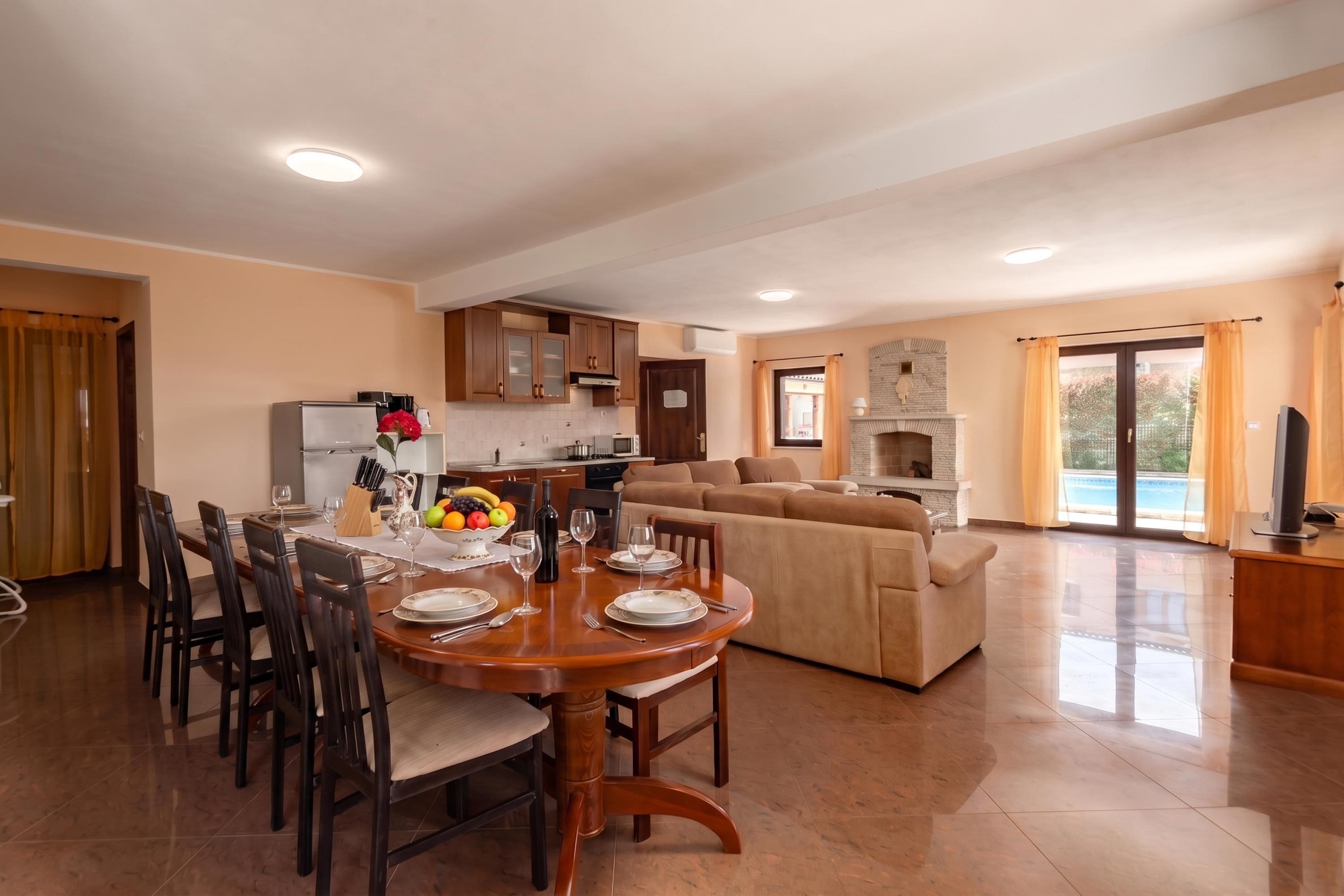 A spacious living area with a dining table set for six, a sofa, and a fireplace.