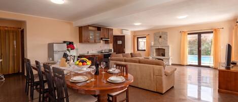 A spacious living area with a dining table set for six, a sofa, and a fireplace.