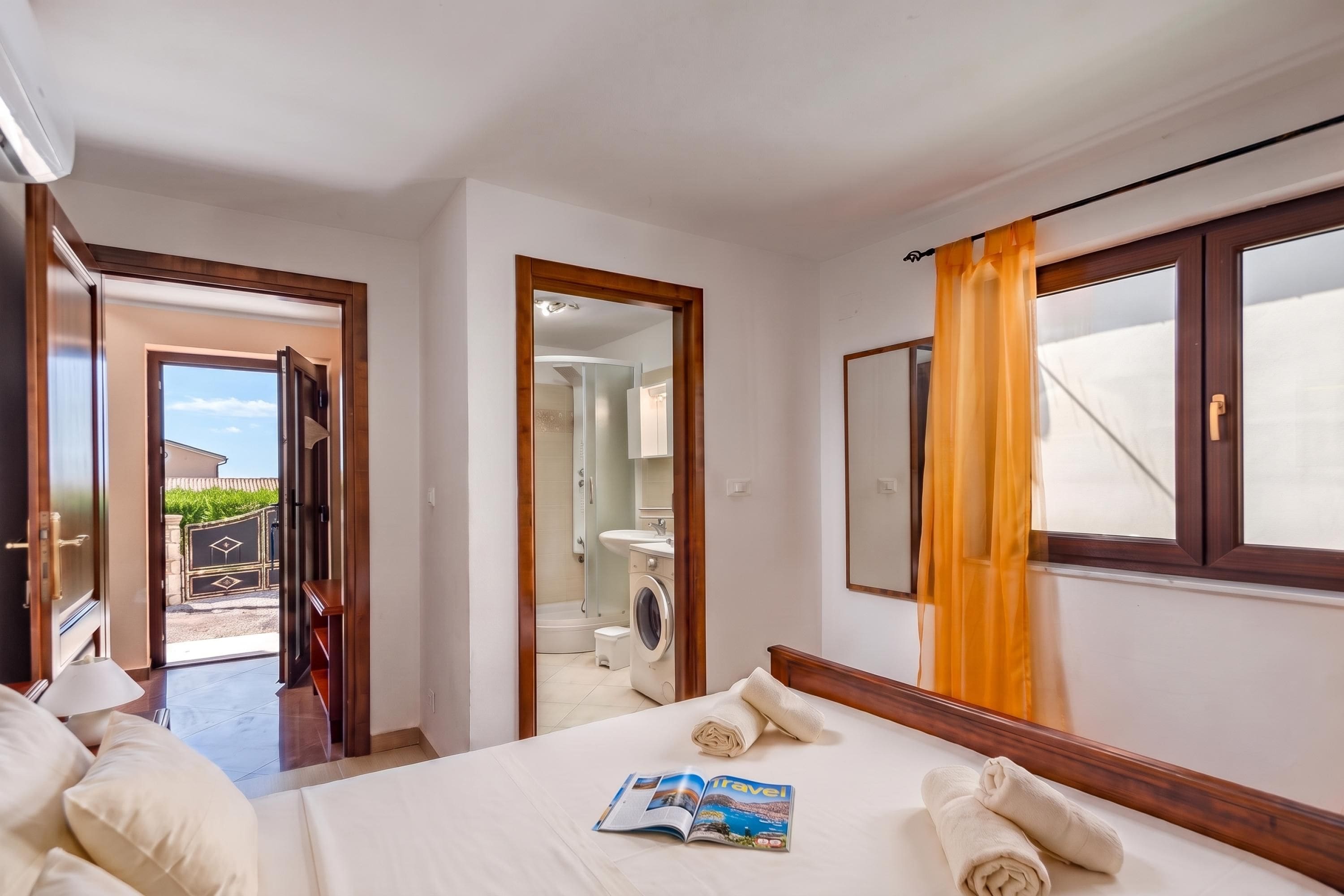A hotel room with a bed, a bathroom, and a view of the outside.