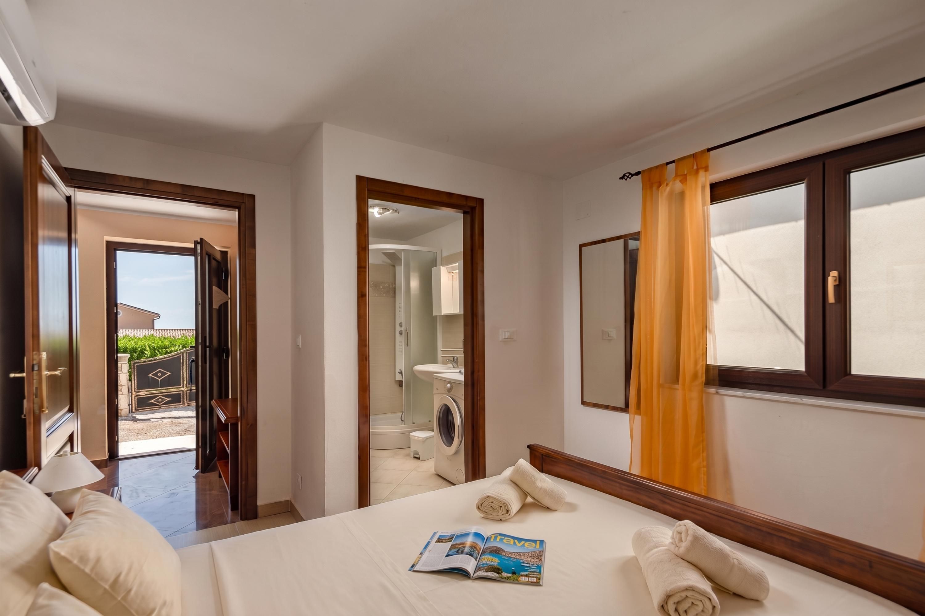 Habitación de hotel con cama, baño con ducha y vistas al exterior.