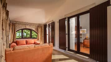 A hallway with a sofa, a stone wall, and a large window with curtains.