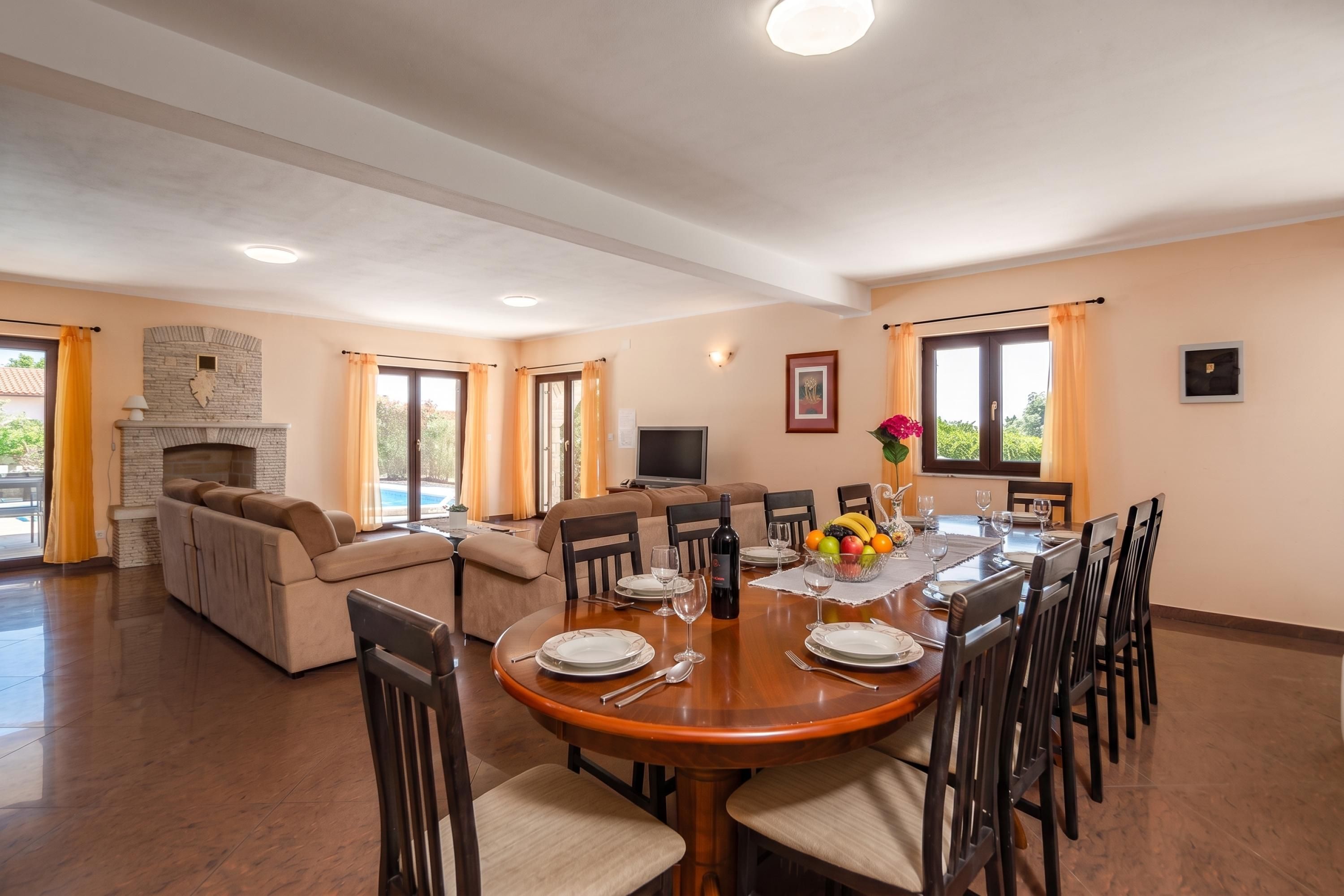 Amplia sala de estar con chimenea, un sofá, una mesa de comedor lista para seis personas y un televisor.
