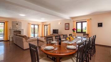 Amplia sala de estar con chimenea, un sofá, una mesa de comedor lista para seis personas y un televisor.