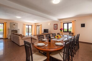 A spacious living area with a fireplace, a sofa, a dining table set for six, and a television. - Pool House Suzi in Heart of Istria (Barban)