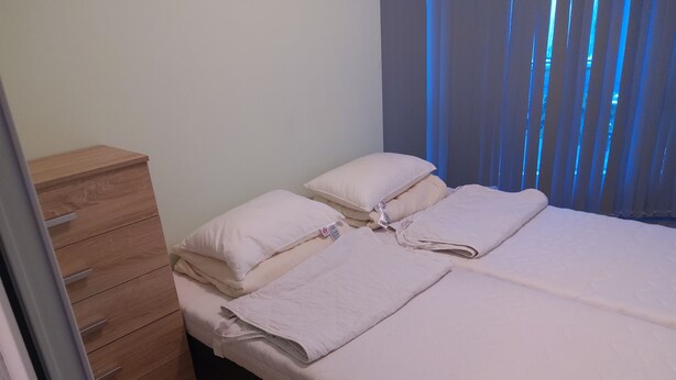 A bedroom with two beds, a wooden dresser, and a window with blue curtains. - 3 rooms by the Black Sea (Sonnenstrand)