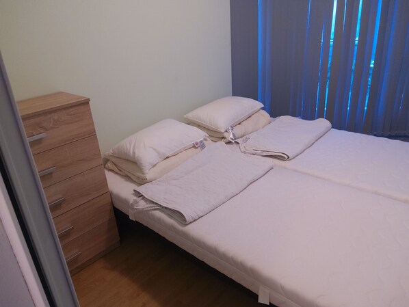 A bedroom with two beds, a wooden dresser, and a window with blue curtains. - 3 rooms by the Black Sea (Sonnenstrand)