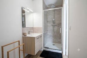 Une salle de bain moderne avec une douche à parois de verre, un lavabo et un miroir.