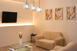 A living room with a sofa, a glass coffee table, a TV, and three pendant lights. - Modern vacation home in Reggio Calabria, a 10-minute walk from the airport. (Reggio Calabria)