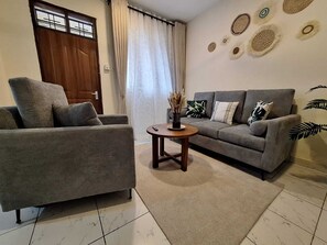 Ein Wohnzimmer mit einer Couch, einem Sessel und einem kleinen runden Tisch mit einer Vase.