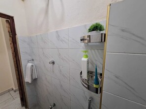 Ein Badezimmer mit Marmorfliesen, einem Handtuchhalter, einer kleinen Pflanze und einem Spiegel.