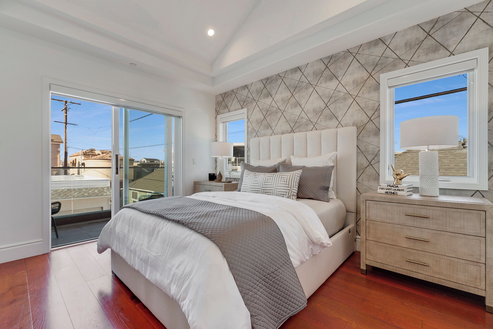 Un dormitorio con cama, mesita de noche, cómoda y un ventanal grande.