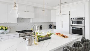 A modern kitchen with white cabinetry, stainless steel appliances, and a marble countertop. - OCEANFRONT MODERN LUXURY W/ROOFTOP (Newport Beach)