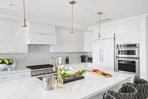 Una cocina moderna con armarios blancos, electrodomésticos de acero inoxidable y encimera de mármol.