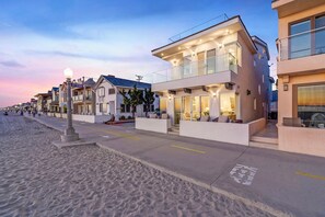 Una propiedad frente a la playa con diseño moderno, que cuenta con techo plano, amplios ventanales y un balcón.