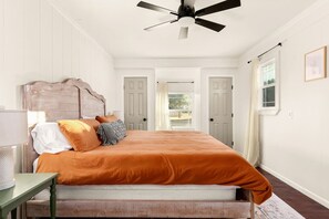 A bedroom with a bed, a ceiling fan, a nightstand, and a window. - Shady Oak: Pool, Hot Tub, Game Room | Sleeps 12 (Fredericksburg)
