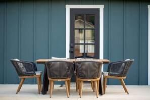 A dining area with a table and four chairs, a door, and a blue wall. - Shady Oak: Pool, Hot Tub, Game Room | Sleeps 12 (Fredericksburg)