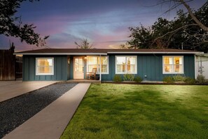 A two-story house with a front porch, a driveway, and a well-maintained lawn. - Shady Oak: Pool, Hot Tub, Game Room | Sleeps 12 (Fredericksburg)